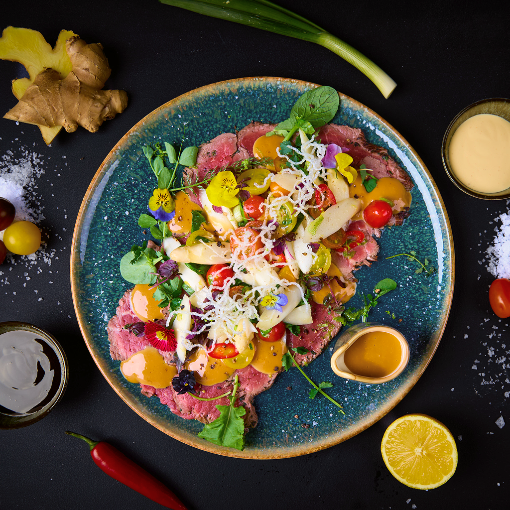 Carpaccio mit Rinderfilet, weißem Spargel, Kirschtomaten, Frühlingslauch, Chili, Basilikum und Fusion Teriyaki-Hollandaise Sauce.
