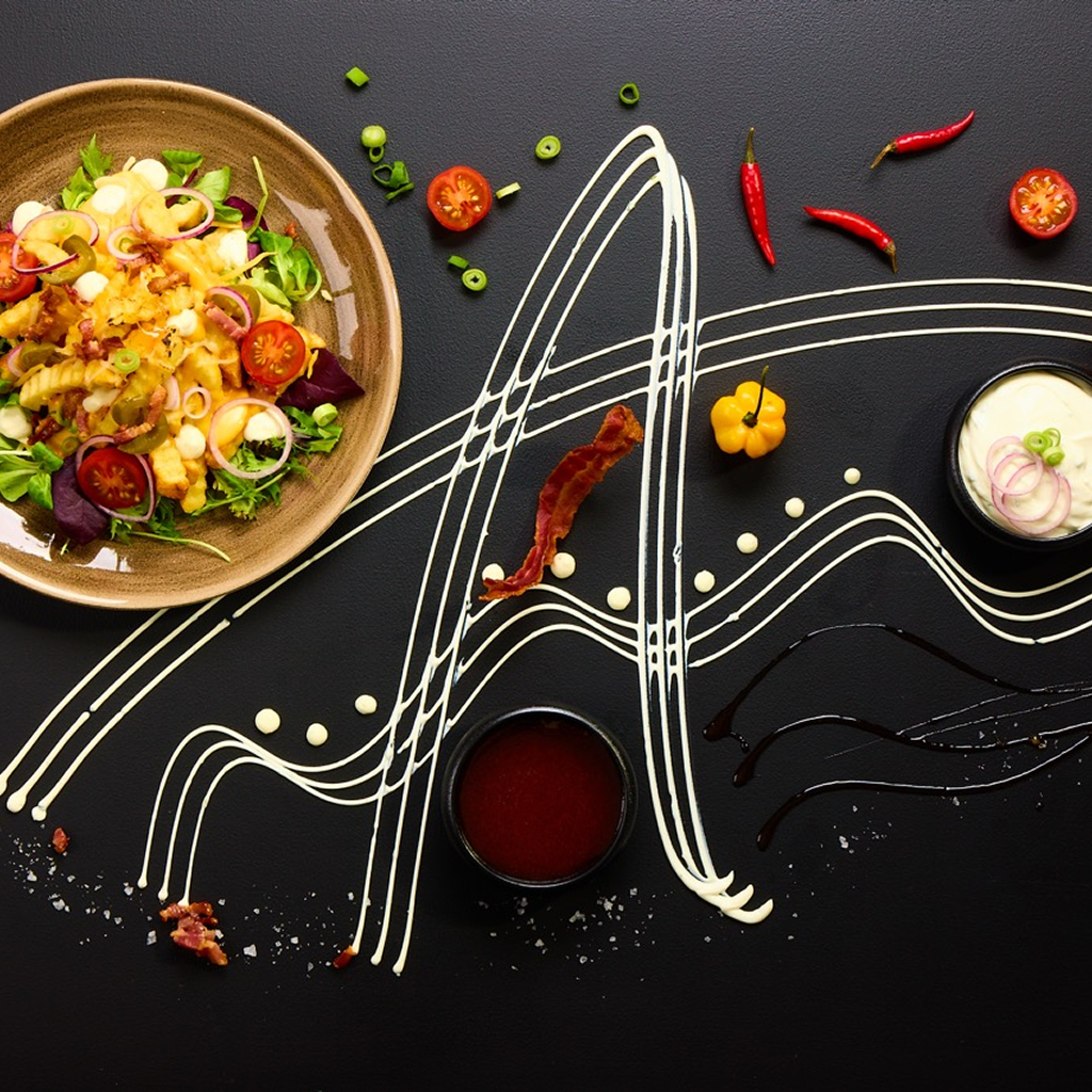 Pommes frites mit Mozzarella, Jalapeños, knusprigem Bacon, Frühlingslauch, Kirschtomaten, Sour Creme und Hot Honey Sauce