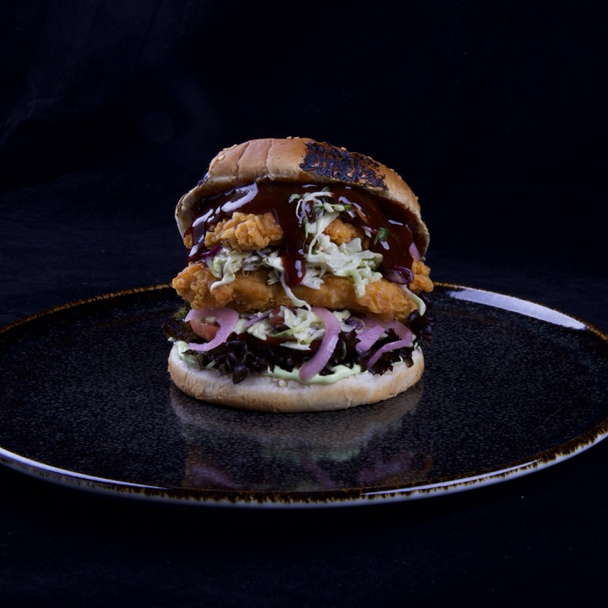 Burger mit Crunchy Chicken Burger Patty, Korean BBQ Sauce, Wasabi-Spitzkohl, Pink Onions, Lollo Rosso und gerösteten Erdnüssen