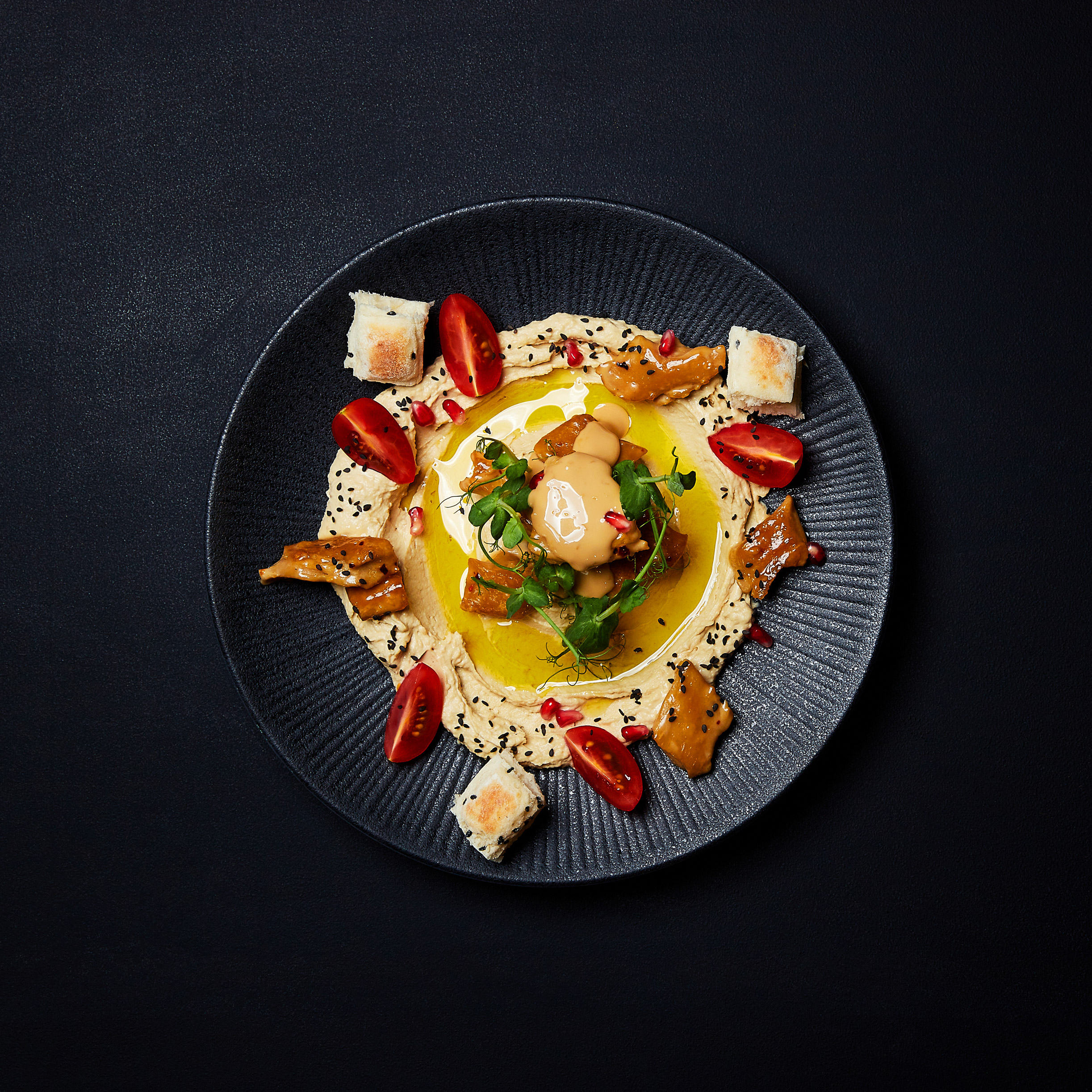 Tellergericht mit Hummus, Planted.Chicken natur, Roasted Sesame Sauce, jungen Erbsensprossen, Kirschtomaten, Granatapfelkernen und schwarzem Sesam